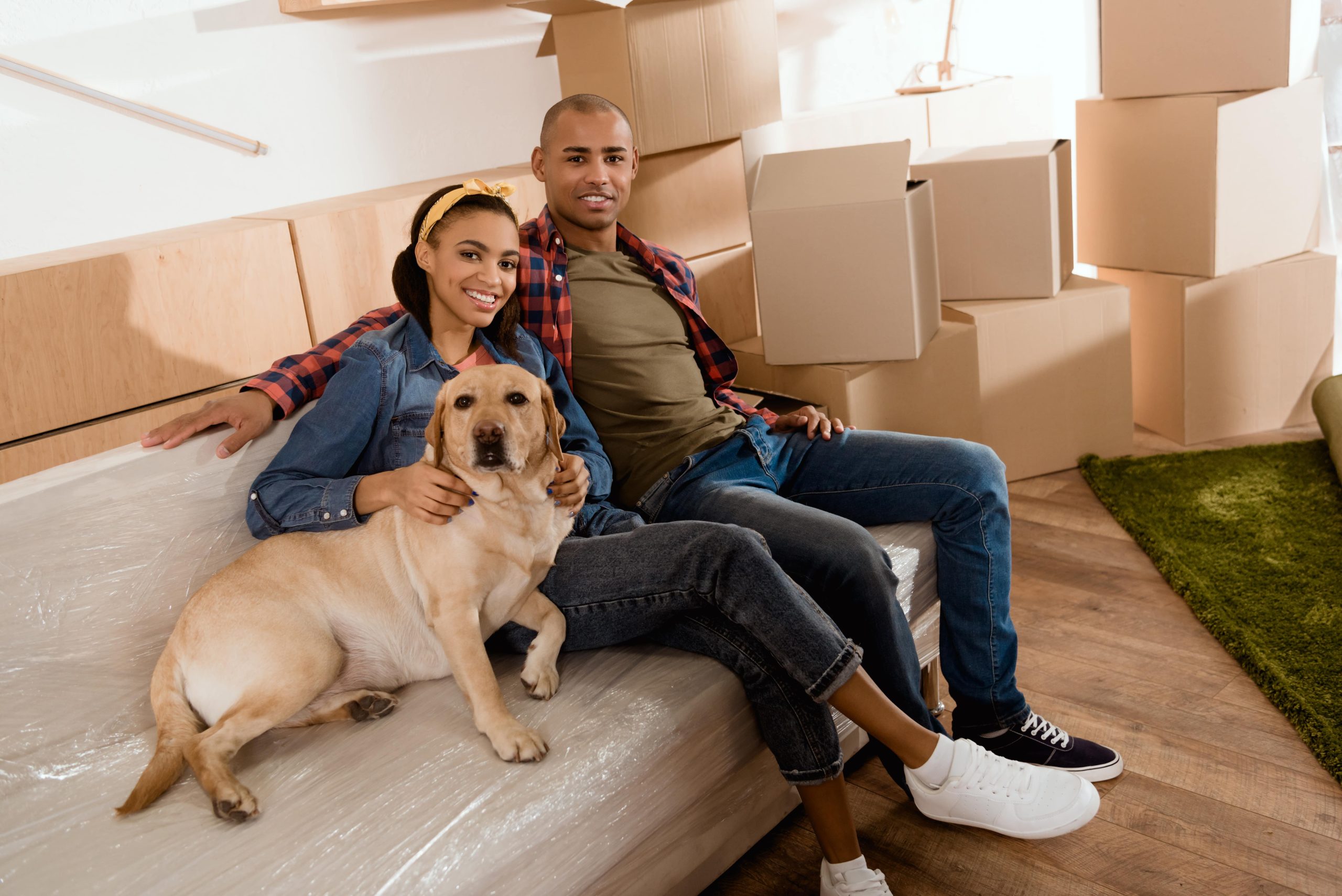 New happy homeowners relaxing on couch with their dog